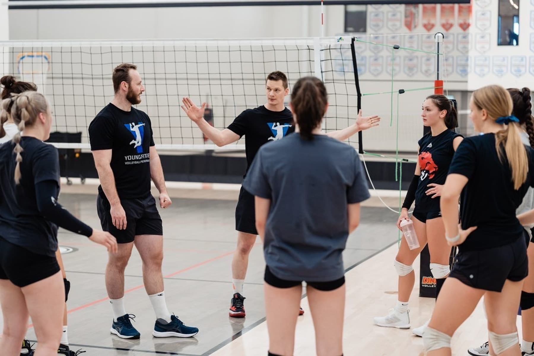 YF Volleyball Athlete Trainer coaches working with athletes at the net